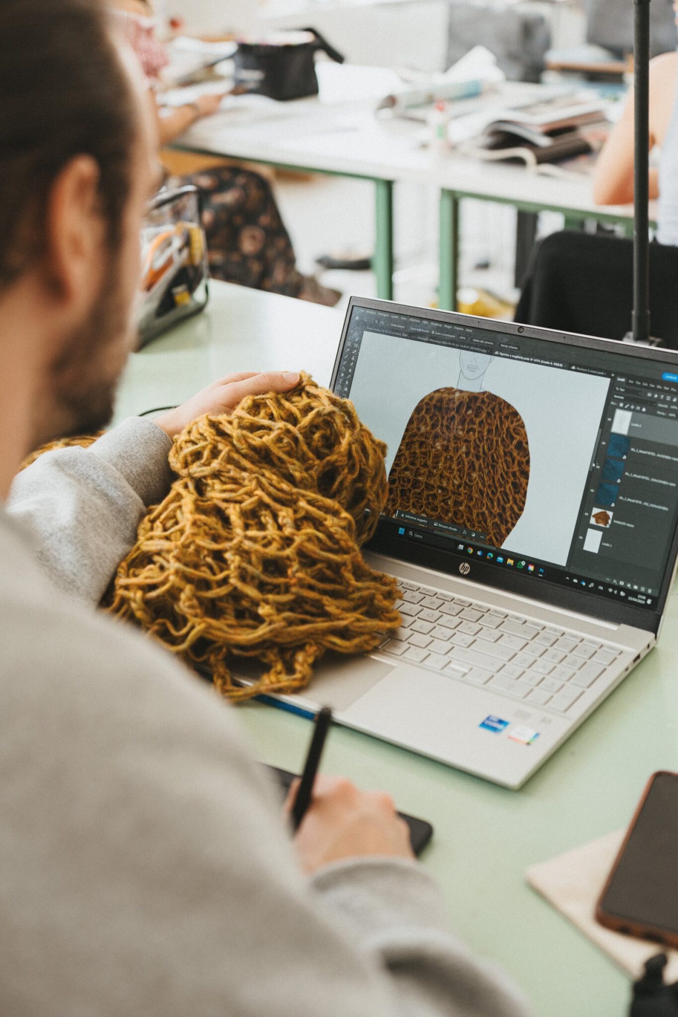 Estudiante diseñando una prenda de punto junto a un ovillo de lana