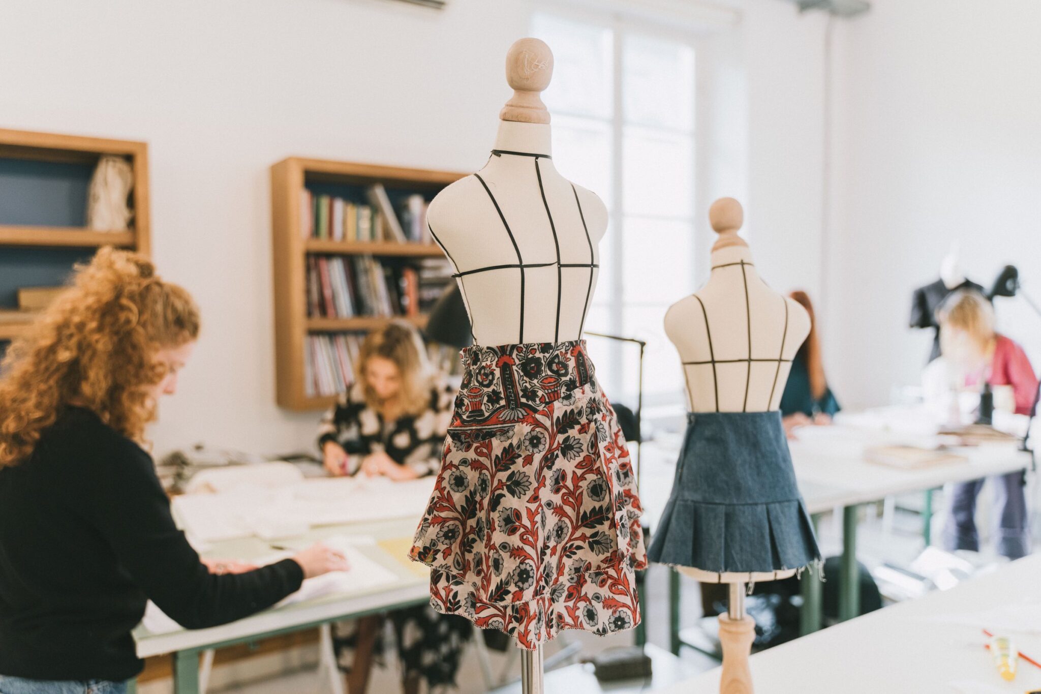 Estudiantes trabajando en el taller de moda junto a los maniquíes